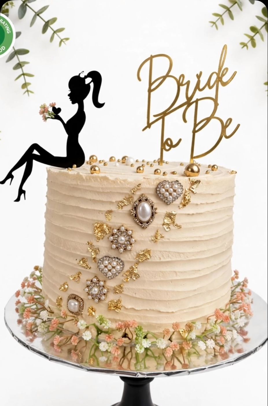 A cream cake with gold detailing and a Bride To Be topper