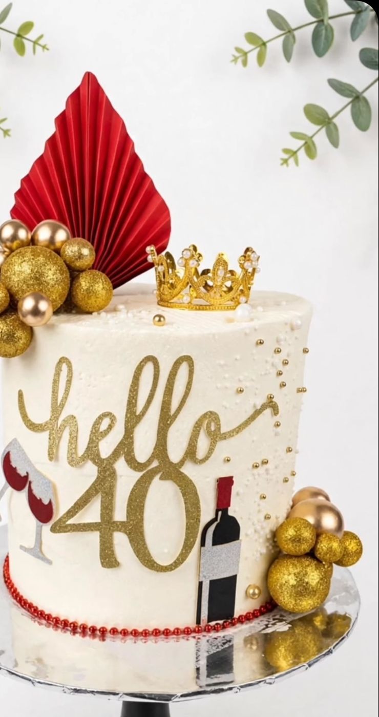 A white and gold 40th birthday cake with a crown and red fan